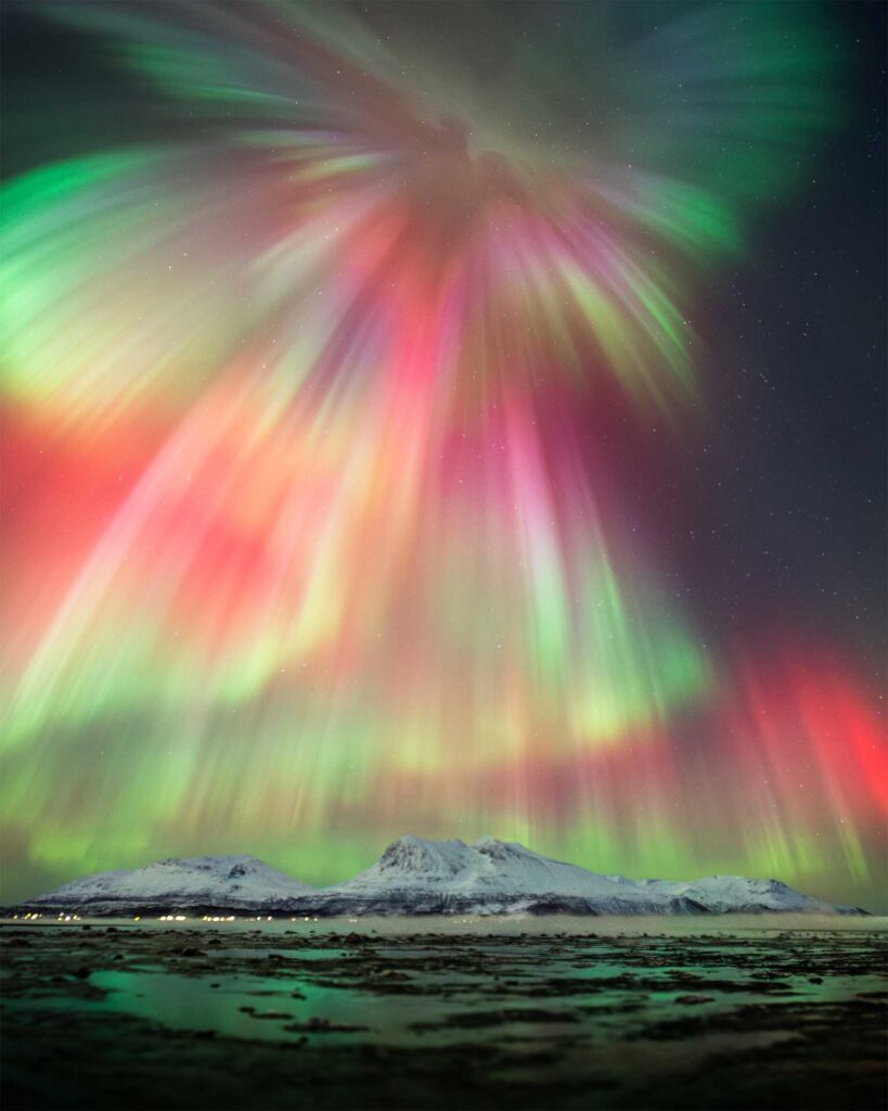 Colourful aurora corona filling the night sky above mountains near Tromsø